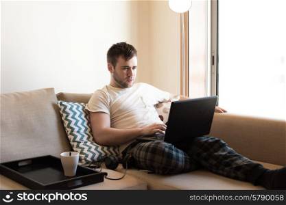 Man sitting on sofa with laptop and a cup of coffee
