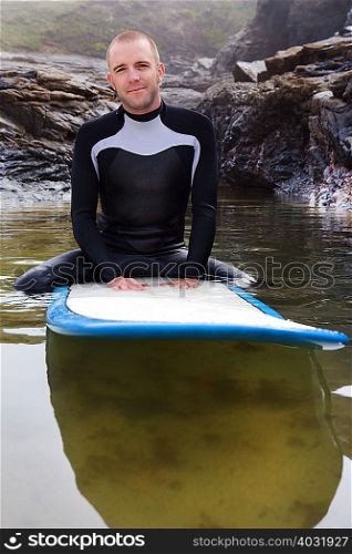 Man sitting on surfboard in the water