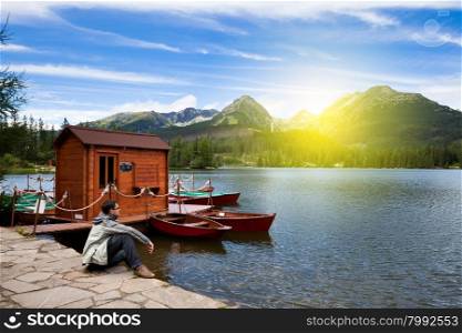 Man sitting on the bank of alpine mountain lake