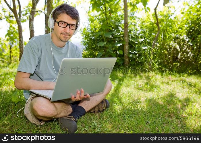 man sitting on the grass working with a laptop