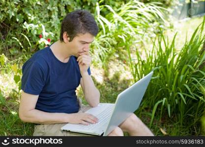man sitting on the grass working with a laptop