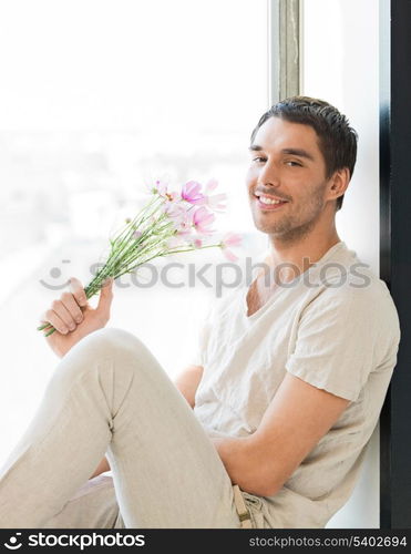 man sitting on the windowsill holding bouquet of flowers...