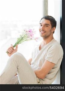 man sitting on the windowsill holding bouquet of flowers...