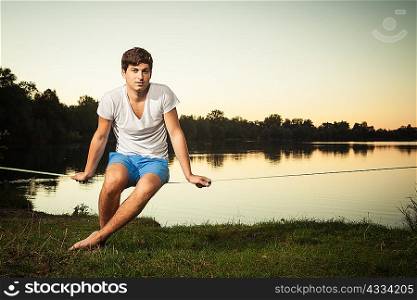Man sitting on tight rope outdoors
