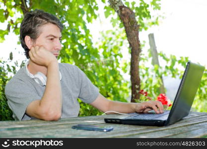 man sitting outdoor working with a laptop