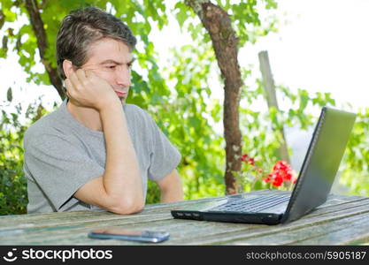 man sitting outdoor working with a laptop