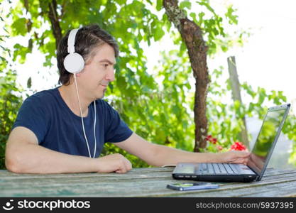 man sitting outdoor working with a laptop