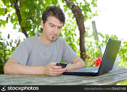 man sitting outdoor working with a laptop