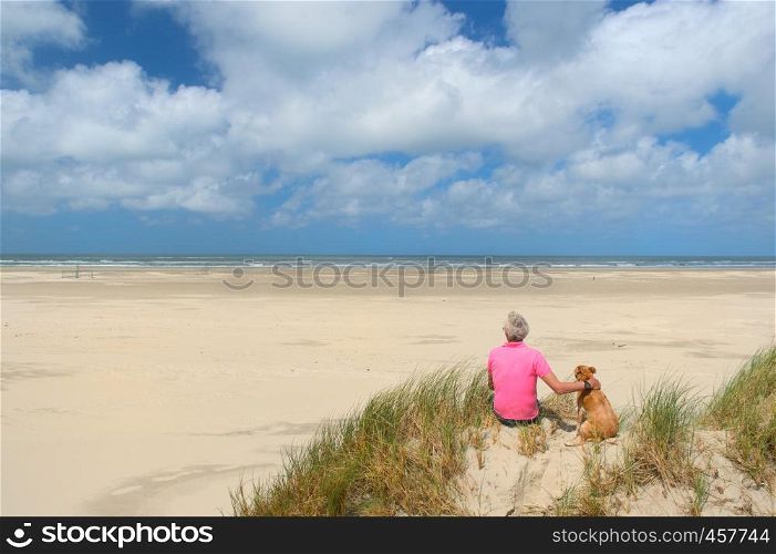 Man sitting with the dog at the beach