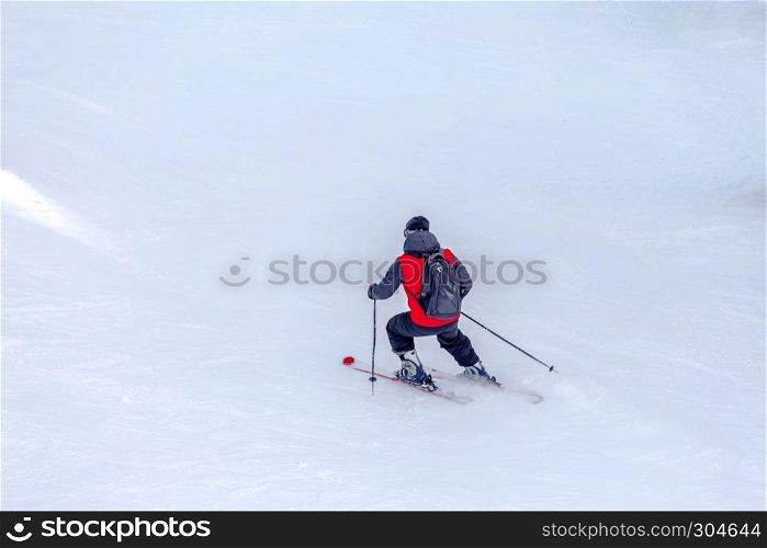 Man skier with red coat and black backpack skiing on fresh white snow on ski slope on Sunny winter day with Copy space in uludag mountain Bursa,Turkey.. Man skier with red coat and black backpack skiing