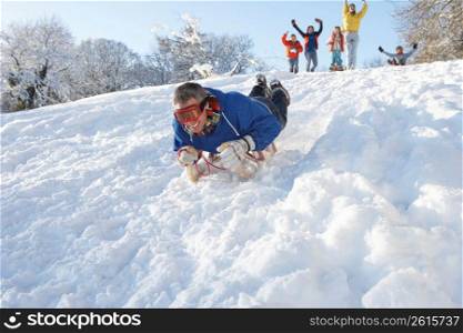 Man Sledging Down Hill With Family Watching