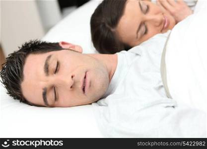 Man sleeping deeply next to his girlfriend