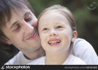 Man smiles proudly holding girl on his knee