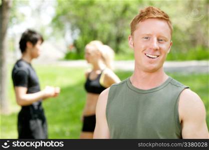 Man smiling and looking at camera while friends talking in the background