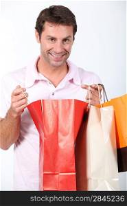 Man smiling holding three shopping bags