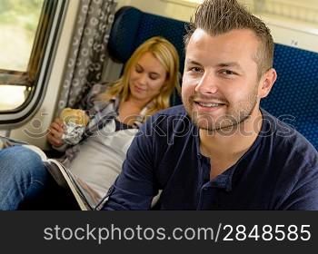 Man smiling sitting on train woman sandwich vacation traveling journey