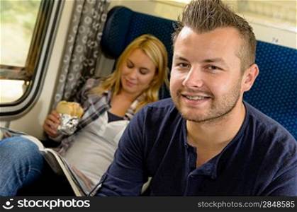Man smiling sitting on train woman sandwich vacation traveling journey