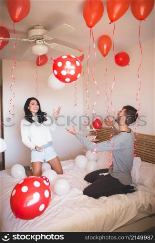 man smiling while his girlfriend looks room full red balloons