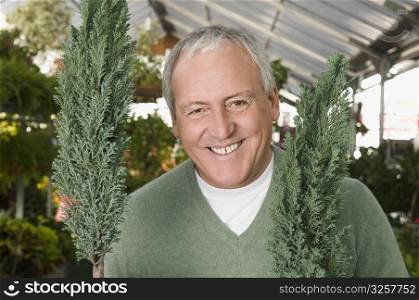 Man smiling with potted plants in a garden center