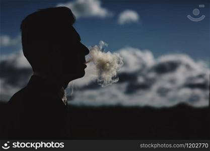 man smokes a cigar and releases smoke. silhouette of smoking man. profile silhouette of a business man who smokes.. man smokes a cigar and releases smoke. silhouette of smoking man. profile silhouette of a business man who smokes