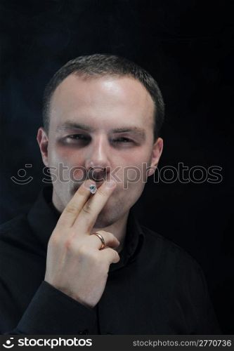 man smokes a cigarette in a dark background
