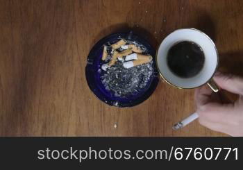 Man smoking a cigarette and drinking cup of coffee