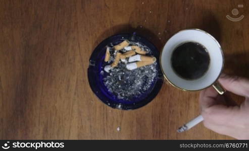 Man smoking a cigarette and drinking cup of coffee