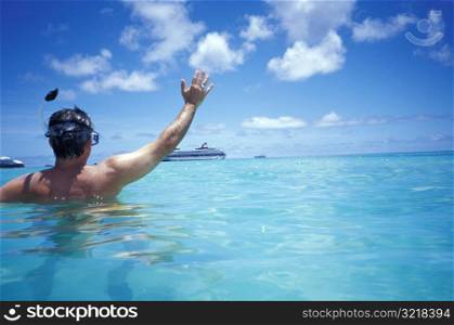 Man Snorkeling and Waving at Cruise Ship