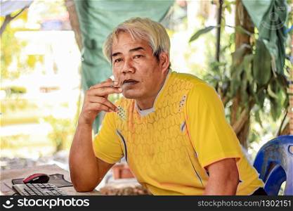 man solemnly smoking a cigarette in staring on front of him with smoke