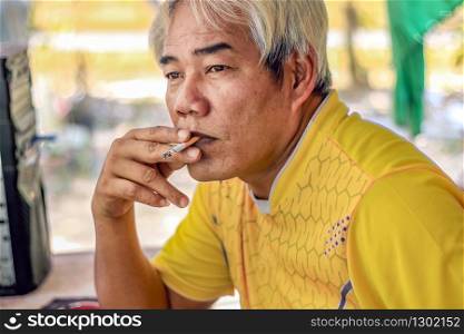 man solemnly smoking a cigarette in staring on front of him with smoke