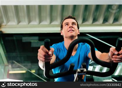 Man spinning in the gym, exercising his legs doing cardio training on bicycle