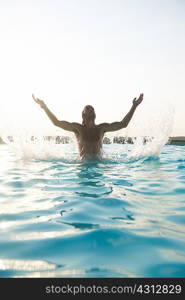 Man splashing water in outdoor swimming pool