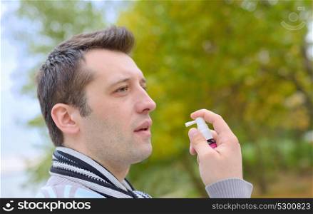 Man spraying with nasal spray in autumn time