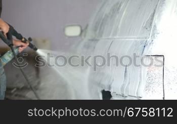 man sprays soapsuds on the car