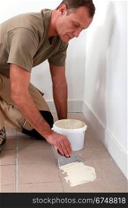 Man spreading tile adhesive on old tiles