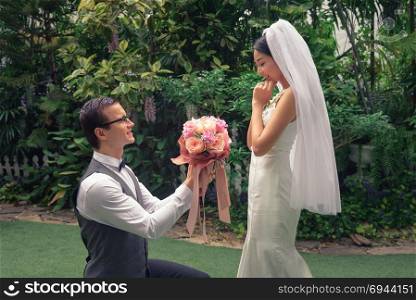 man stand on knee with flower make a proposal to get married to beautiful girlfriend, engagement concept