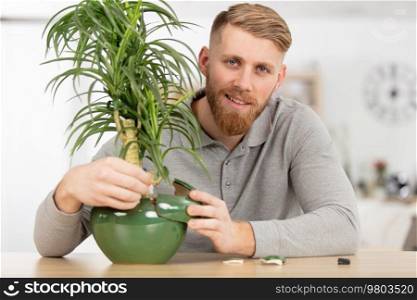 man standing at home near a plant