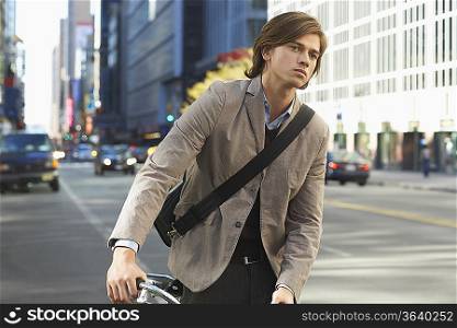 Man standing by bicycle on busy street