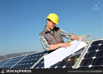 Man standing by solar panels with construction plan