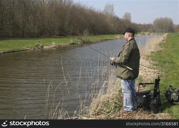 Man standing by the waterside with his fishing rod