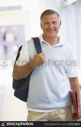 Man standing in corridor with backpack (high key)
