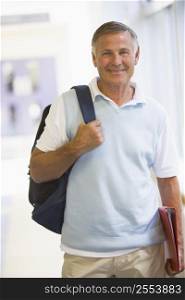 Man standing in corridor with backpack (high key)