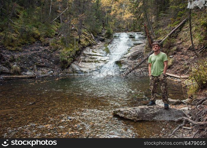 Man standing in front of waterfall in Altai mountains. Traveling to the waterfall