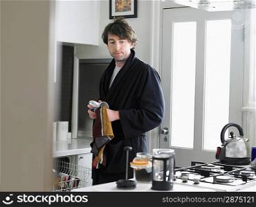 Man standing in kitchen empting dishwasher