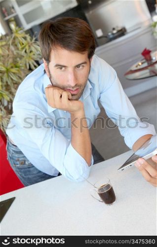 Man standing in kitchen with electronic tablet