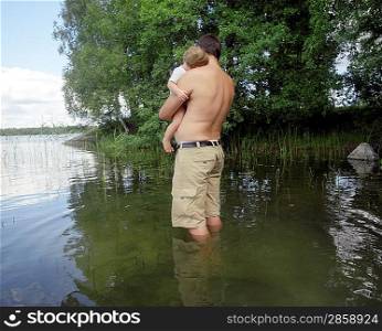 Man Standing in Lake Holding Son