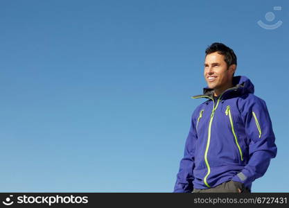 Man Standing In Snow Wearing Warm Clothes On Ski Holiday In Mountains