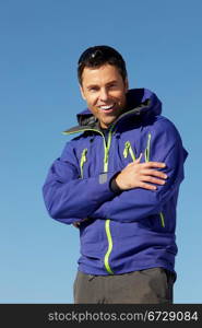 Man Standing In Snow Wearing Warm Clothes On Ski Holiday In Mountains