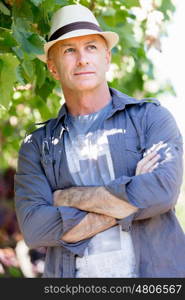 Man standing in vineyard. Man wearing hat standing in vineyard