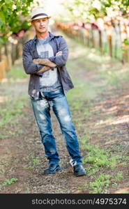 Man standing in vineyard. Man wearing hat standing in vineyard